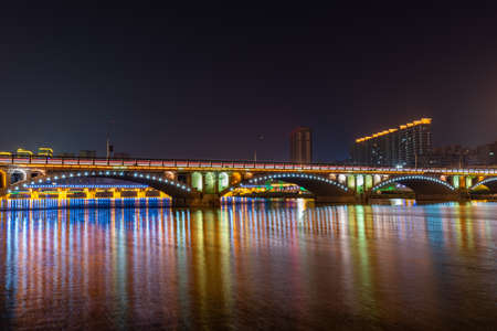 In the city at night, colorful lights are reflected in the water of the riverの写真素材