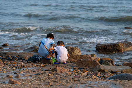 The back of two children playing upstream of the beach.の写真素材