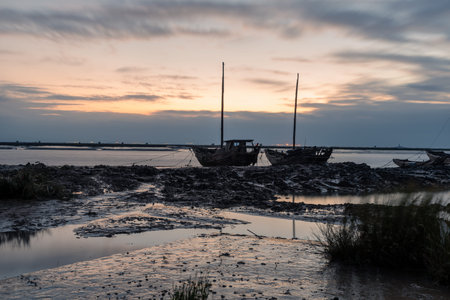 In the shallow area before sunrise in the morning, there are cloudy clouds and many fishing boats on the beachの写真素材