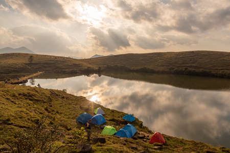 The natural lake on the meadow has many tents by the lakeの写真素材