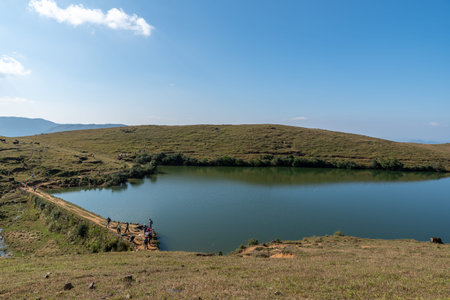 Under the blue sky, the natural lake on the meadow has yellow grass and blue water