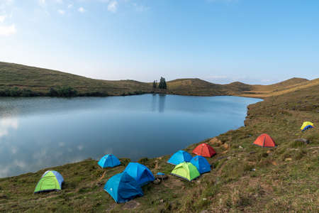 The natural lake on the meadow has many tents by the lakeの写真素材