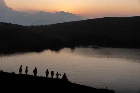 Silhouettes of campers by the lake at duskの写真素材