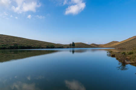 The meadow by the lake is blue and the water is blue and the grass is yellowの写真素材