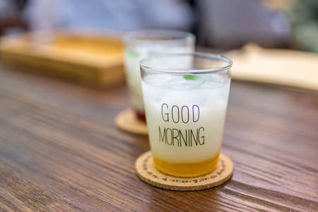 Two white iced drinks with the word "good morning" written on them are on the wooden tableの写真素材