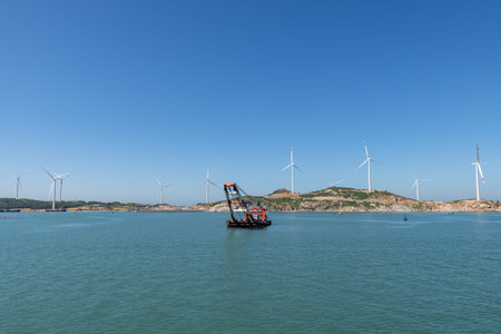 On the island in the middle of the sea, many wind turbines are installed under the blue sky