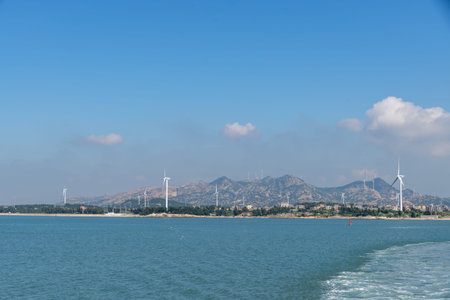 On the island in the middle of the sea, many wind turbines are installed under the blue skyの写真素材
