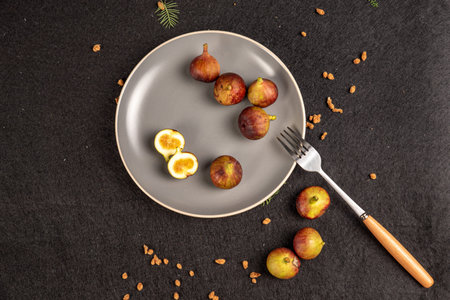 Sliced and intact figs on a gray plate on a black background