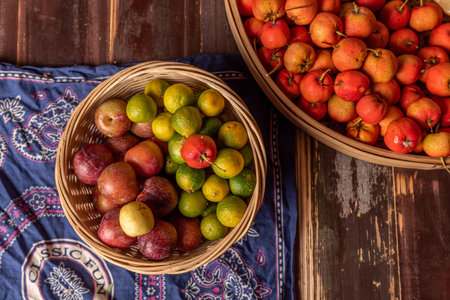 Many colors and varieties of fruit are either on the plate or scattered on the wooden table