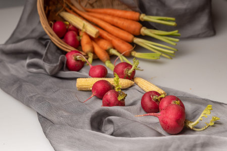 The red and orange radishes are on the white cloth