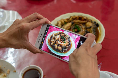 A man is taking pictures with a mobile phone in his handの写真素材