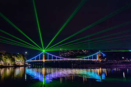 At night, the stream reflects the colorful lights on the bridgeの写真素材
