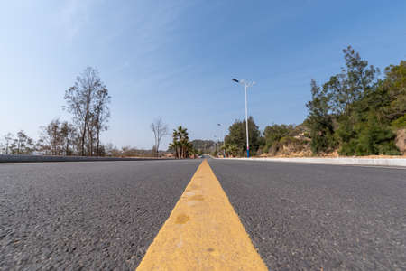 The asphalt road leading to the distance is under the blue skyの写真素材