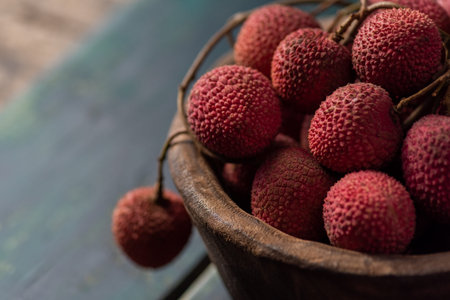 Litchi is placed in a wooden plate, peeled or unopened, on a dark wood grain table