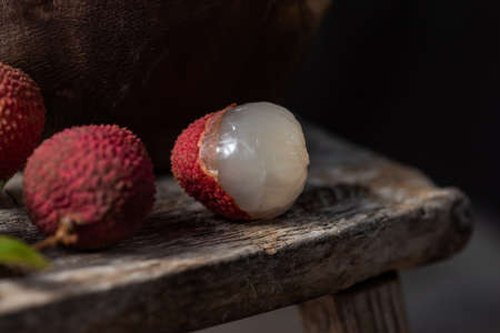Litchi is placed in a wooden plate, peeled or unopened, on a dark wood grain tableの写真素材