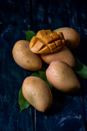 Cut and complete mangoes on a plate in a dark environmentの写真素材