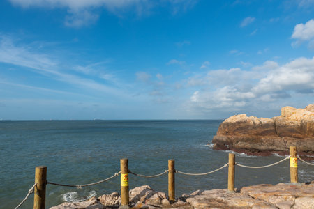 In the morning, the sun shines on the rocks and waves on the beach;の写真素材