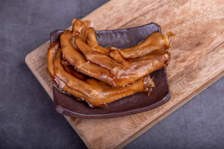 The stewed duck claws in the container are in a dark backgroundの写真素材