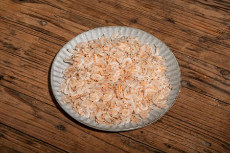 The dried small shrimps in the bowl or plate are on the wooden tableの写真素材