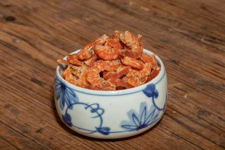 Shelled fresh shrimps on a plate or bowl are on a wood colored tableの写真素材