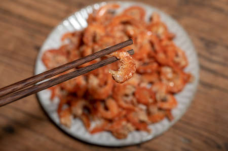 Shelled fresh shrimps on a plate or bowl are on a wood colored tableの写真素材
