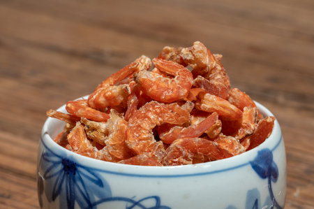 Shelled fresh shrimps on a plate or bowl are on a wood colored tableの写真素材