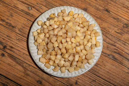 The plates or bowls in the wooden table contain scallopsの写真素材