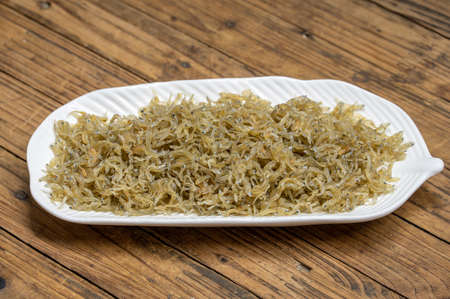 The dried clove fish in the container is on the wood grain tableの写真素材