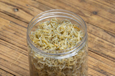 The dried clove fish in the container is on the wood grain tableの写真素材