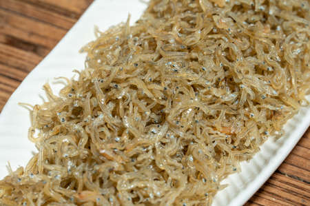 The dried clove fish in the container is on the wood grain tableの写真素材