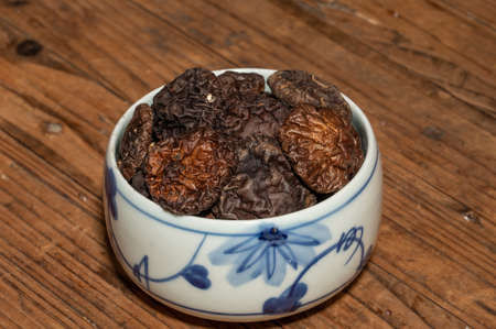 Dried mushrooms in a container on a wooden countertopの写真素材