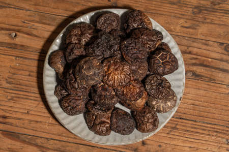 Dried mushrooms in a container on a wooden countertopの写真素材