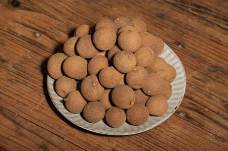 Dried longan in the container on the wood grain tableの写真素材