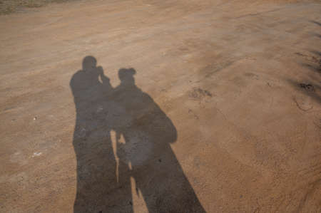 The sun shines two people's shadows on the landの写真素材