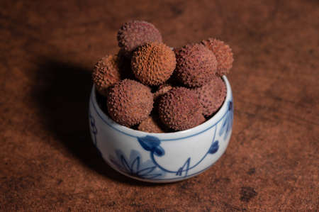 Dried litchi in a bowl on a dark yellow tableの写真素材