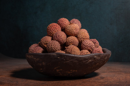 Dried litchi in a bowl on a dark yellow table