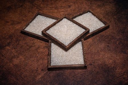 Some square containers of white rice in the dark background