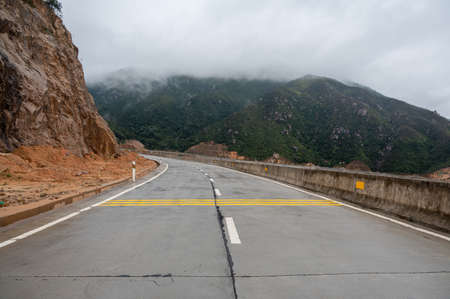 A road leading to the mountains. There is fog on the mountainsの写真素材