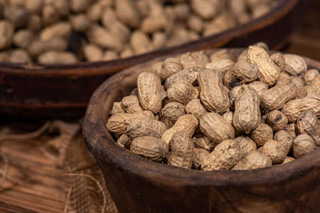 The container on the wood grain table is full of peanutsの写真素材