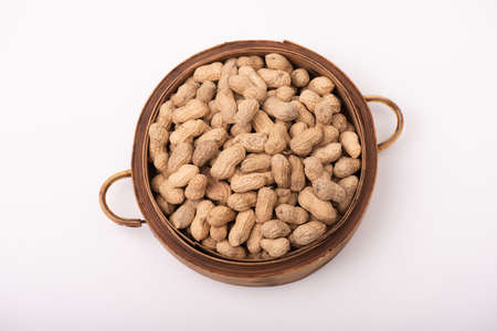 The peanuts in the round plate are on a white backgroundの写真素材