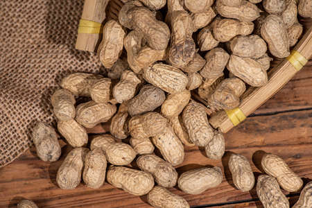 The container on the wood grain table is full of peanutsの写真素材