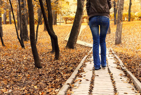 autumn landscape with a lady walking down the roadの写真素材