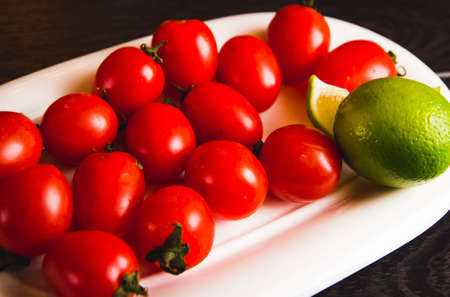 fresh red delicious tomatoes in the heart shape plate on an wooden tabletop with place for textの写真素材