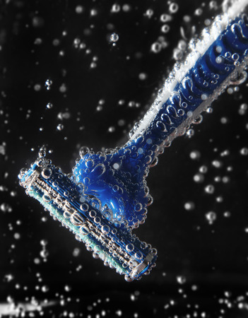 Razor blade close up in cold soda water with bubbles on black backgroundの写真素材