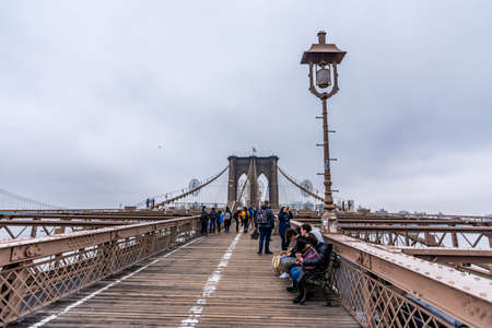new York, US - March 29, 2018: People crossing the Brooklyn bridge on a foggy day in New Yorkのeditorial素材