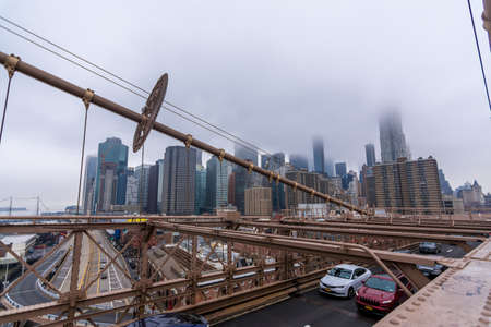 New York, US - March 29, 2018: Downtown Manhattan with buildings obsucured under heavy fog as seen from Brooklyn bridgeのeditorial素材