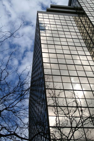 Glass building reflecting tree and sky