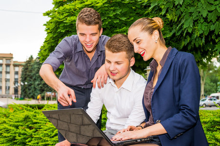 Enthusiastic business people using  laptop outdoors