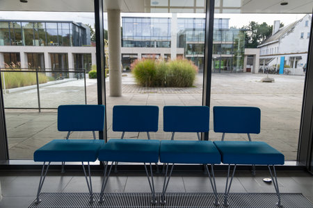 A row of four blue chairs are sitting in front of a windowの写真素材