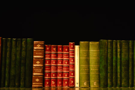 Vintage Leather Bound Books on Wooden Shelf Against Dark Backgroundの写真素材
